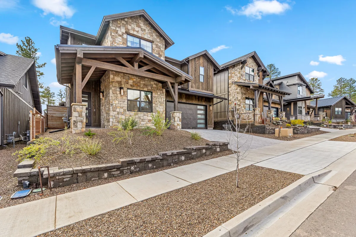 This image features the home's stone façade accented with wood, showcasing its modern exterior architecture and landscaped yard. The setting suggests a welcoming, walkable neighborhood atmosphere, perfect for guests to gather outside or set out for a stroll toward downtown or campus.