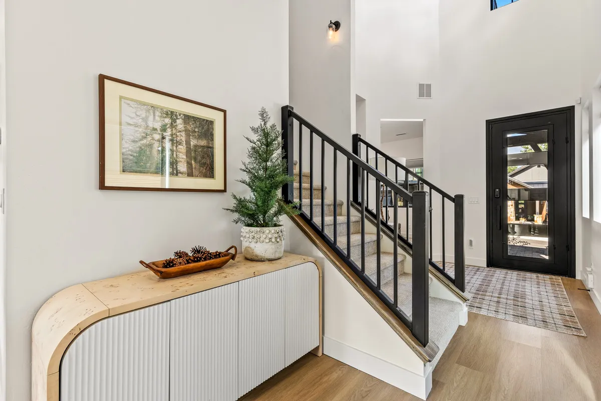 This interior view captures the home’s front entry, featuring a staircase, a welcoming console table, framed artwork, and an indoor plant by the front door. The setting is inviting—a perfect first impression.
